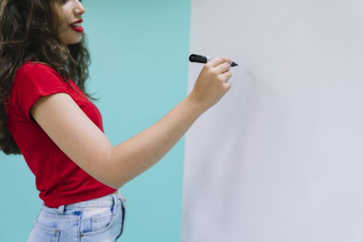 žena sa chystá písať fixkou na bielu tabuľovú stenu