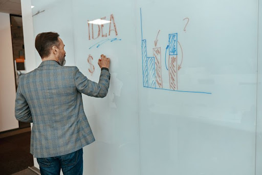 muž kreslí svoje nápady na bielu tabuľu